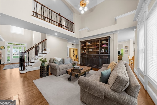 living room featuring baseboards, ornamental molding, wood finished floors, a high ceiling, and stairs