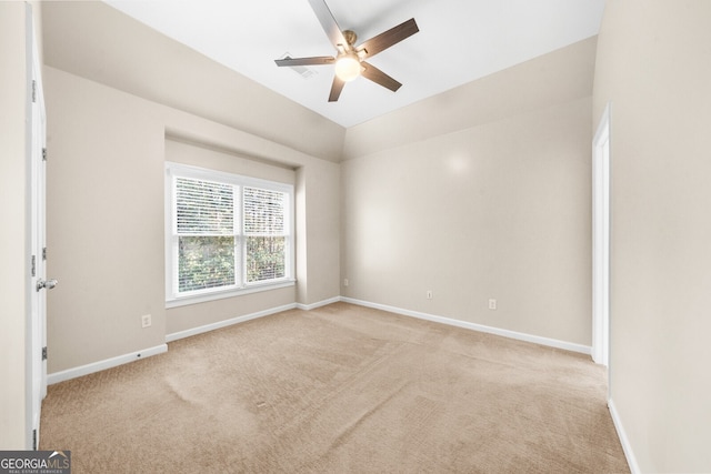 empty room featuring lofted ceiling, ceiling fan, carpet, and baseboards