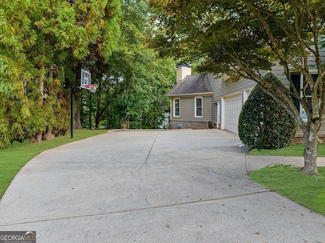 view of front of home with driveway, a garage, a chimney, and a front yard