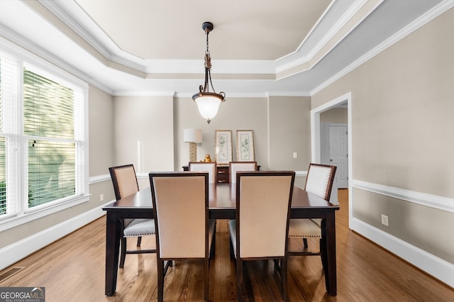 dining area featuring a tray ceiling, wood finished floors, and baseboards