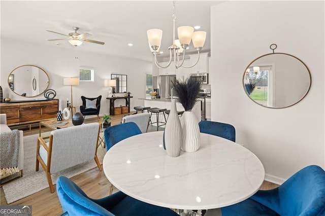 dining room with light wood-type flooring, recessed lighting, baseboards, and ceiling fan with notable chandelier