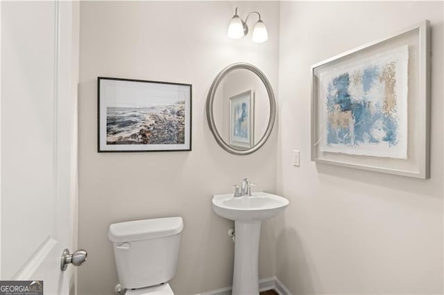 half bath featuring toilet and baseboards