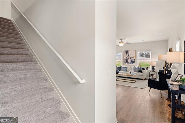 stairway with a ceiling fan, baseboards, and wood finished floors