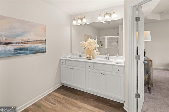 full bath with a stall shower, a sink, baseboards, and double vanity