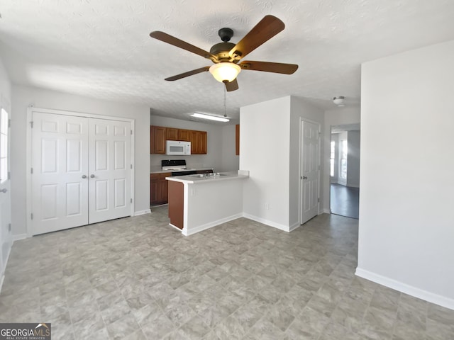 11403 S Grove Dr, Hampton, GA 30228 - kitchen featuring white microwave, a ceiling fan, light countertops, brown cabinetry, and a peninsula
