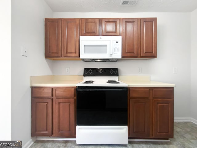 11403 S Grove Dr, Hampton, GA 30228 - kitchen featuring electric range oven, white microwave, light countertops, and brown cabinetry