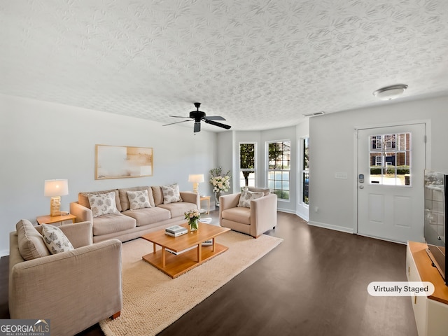 living area featuring a textured ceiling, ceiling fan, visible vents, and baseboards