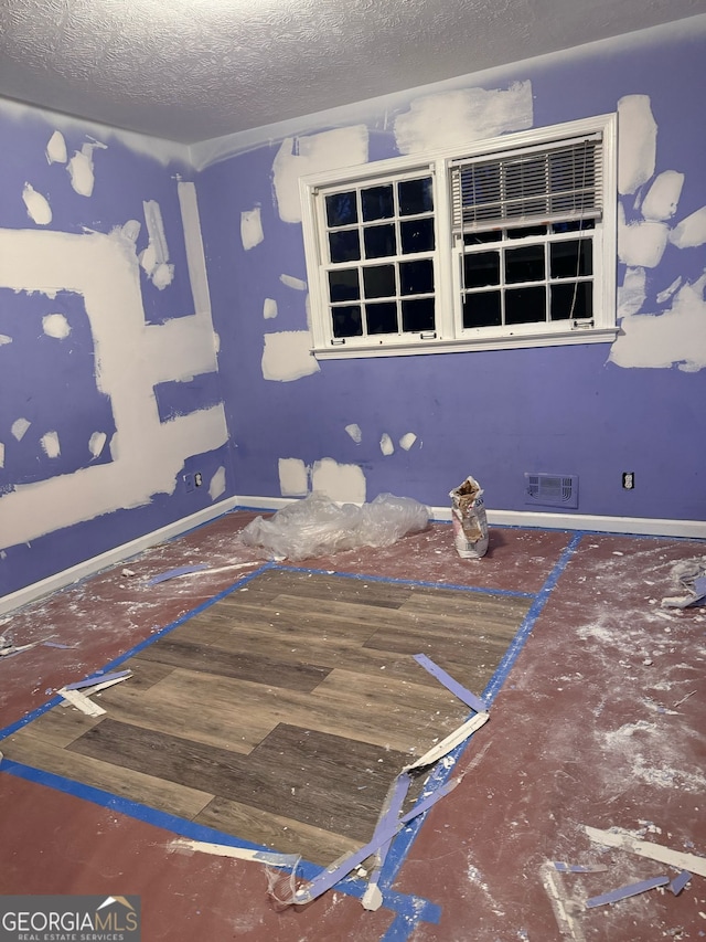 interior space with baseboards, visible vents, and a textured ceiling