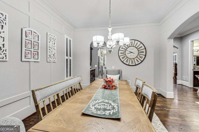 dining area with arched walkways, a decorative wall, wood finished floors, ornamental molding, and an inviting chandelier