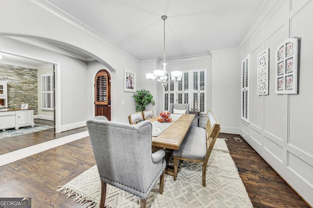 dining room featuring arched walkways, a chandelier, baseboards, dark wood finished floors, and crown molding