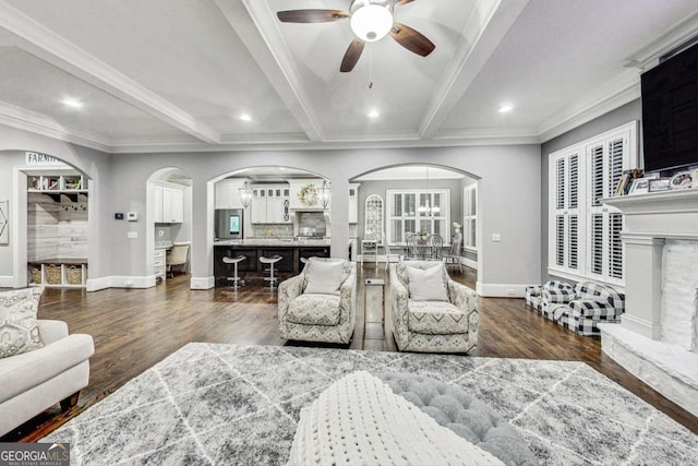 living room featuring baseboards, arched walkways, dark wood-style floors, ornamental molding, and beam ceiling