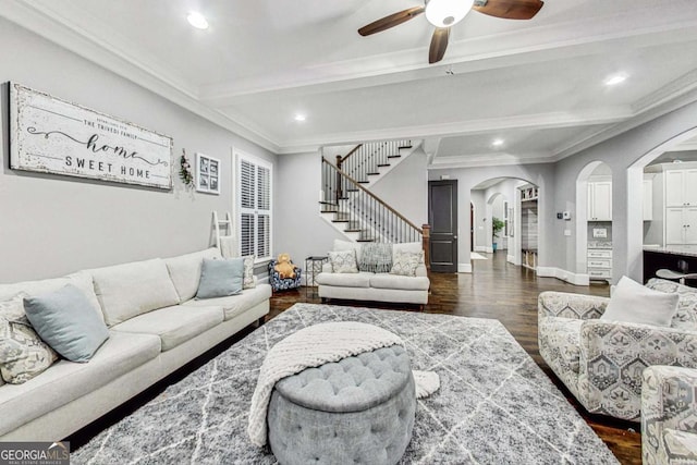 living room with arched walkways, dark wood finished floors, stairway, crown molding, and beam ceiling