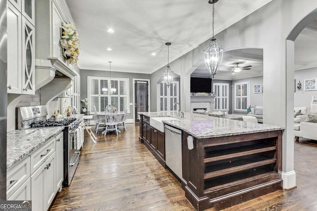 kitchen with dark wood-style floors, arched walkways, stainless steel appliances, open floor plan, and a sink