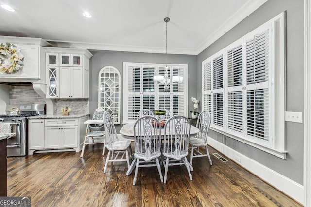 dining space featuring visible vents, baseboards, dark wood finished floors, crown molding, and a notable chandelier