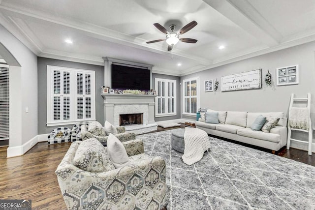 living room featuring arched walkways, beam ceiling, crown molding, wood finished floors, and baseboards