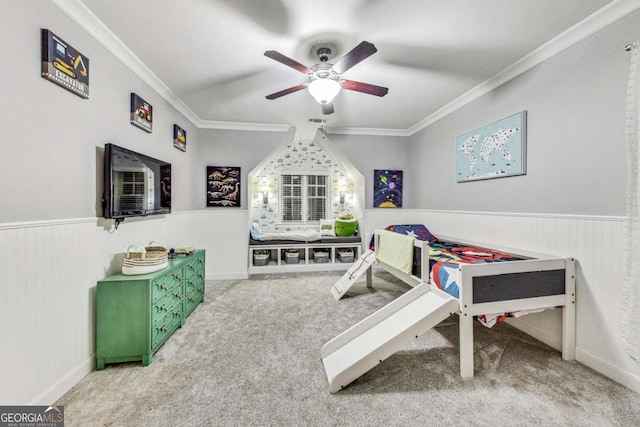 game room with carpet floors, a wainscoted wall, ornamental molding, and a ceiling fan