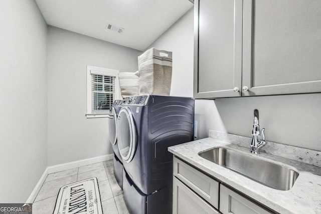 washroom featuring light tile patterned floors, a sink, baseboards, cabinet space, and washer and clothes dryer