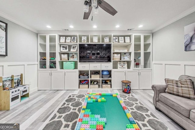 rec room featuring a decorative wall, crown molding, and wood finished floors