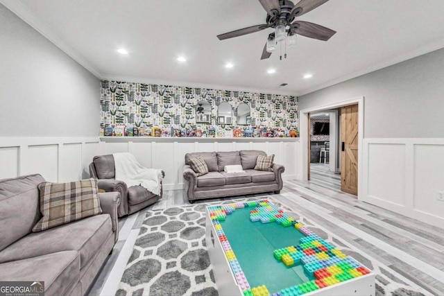 living area with a wainscoted wall, crown molding, recessed lighting, and light wood-style floors