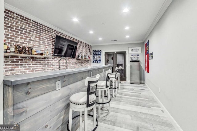 bar with ornamental molding, recessed lighting, light wood-style flooring, and wet bar