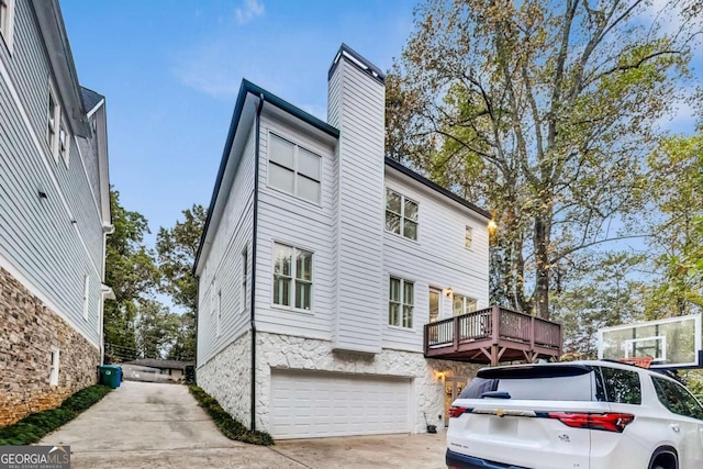 view of home's exterior featuring an attached garage, a chimney, and concrete driveway