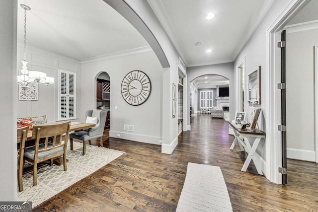 foyer with an inviting chandelier, crown molding, baseboards, and wood finished floors