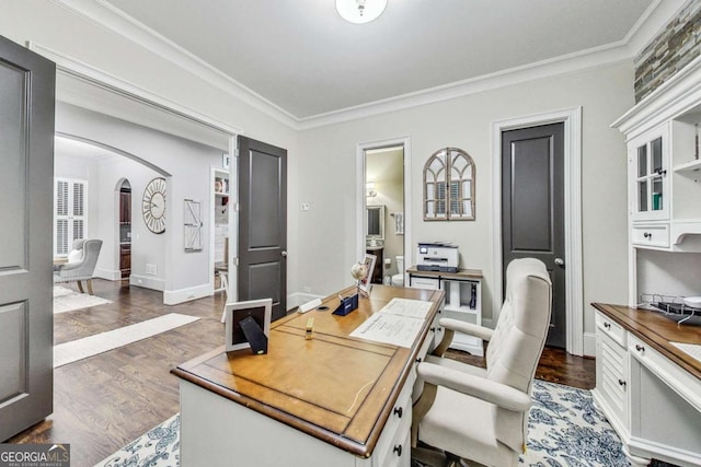 office area featuring arched walkways, ornamental molding, wood finished floors, and baseboards