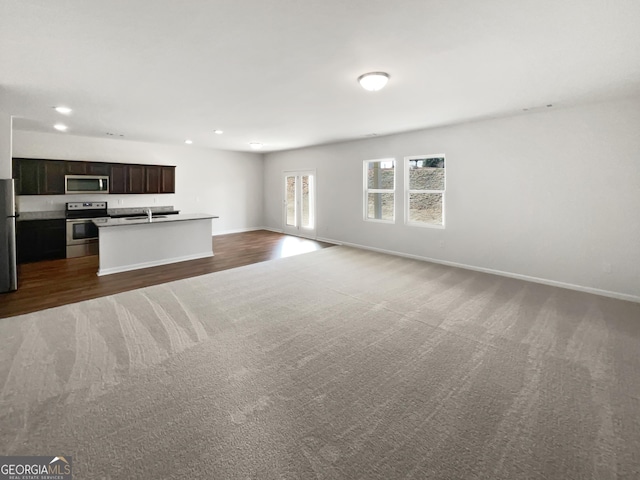 kitchen with recessed lighting, appliances with stainless steel finishes, open floor plan, a kitchen island with sink, and baseboards