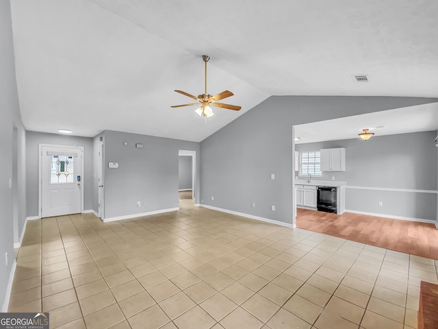 unfurnished living room featuring light tile patterned floors, beverage cooler, vaulted ceiling, and a ceiling fan