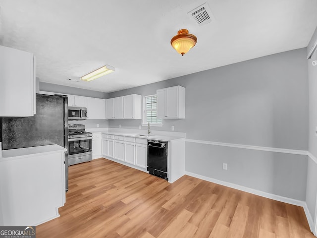 kitchen featuring visible vents, stainless steel appliances, light wood-style floors, white cabinetry, and a sink