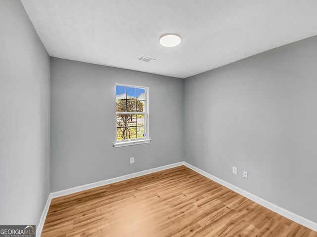 unfurnished room featuring visible vents, baseboards, and wood finished floors