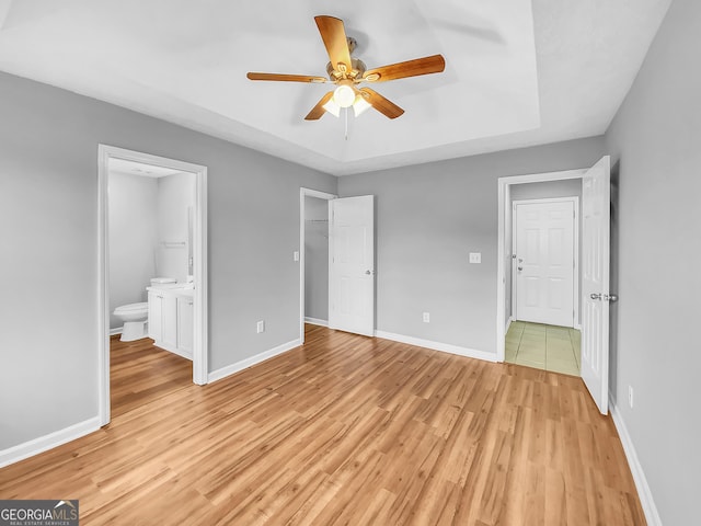 1681 Graystone Dr, Hampton, GA 30228 - unfurnished bedroom featuring light wood-type flooring, a raised ceiling, connected bathroom, a closet, and a walk in closet