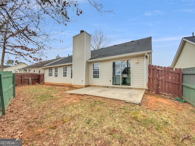 rear view of house featuring a yard, a fenced backyard, a chimney, and a patio