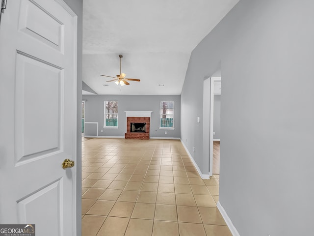 1681 Graystone Dr, Hampton, GA 30228 - unfurnished living room with a ceiling fan, light tile patterned flooring, vaulted ceiling, and a brick fireplace