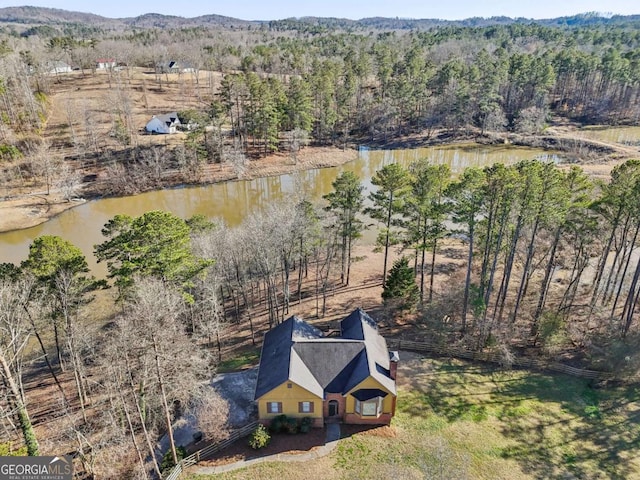 drone / aerial view with a forest view and a water view