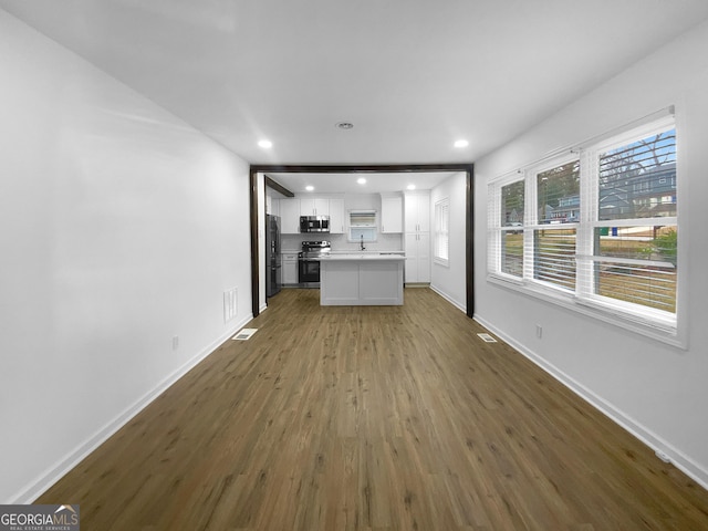 unfurnished living room featuring dark wood-type flooring, recessed lighting, a sink, and baseboards