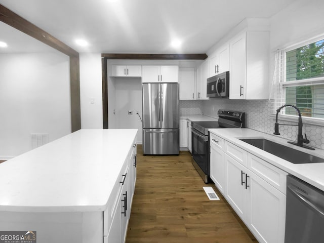 kitchen featuring dark wood-type flooring, a sink, white cabinets, appliances with stainless steel finishes, and backsplash