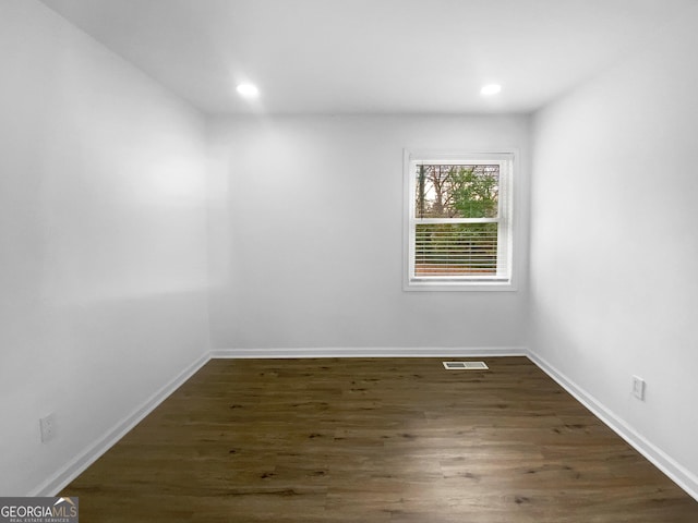 empty room with recessed lighting, dark wood finished floors, visible vents, and baseboards