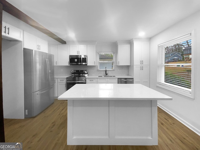 kitchen with tasteful backsplash, white cabinets, appliances with stainless steel finishes, wood finished floors, and a sink