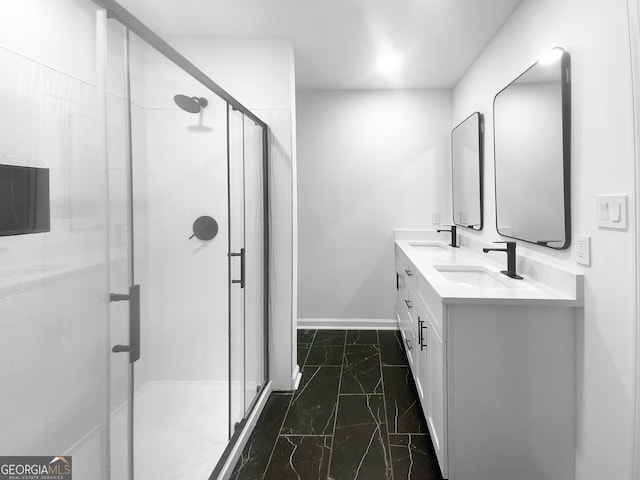 bathroom with double vanity, a shower stall, baseboards, and a sink