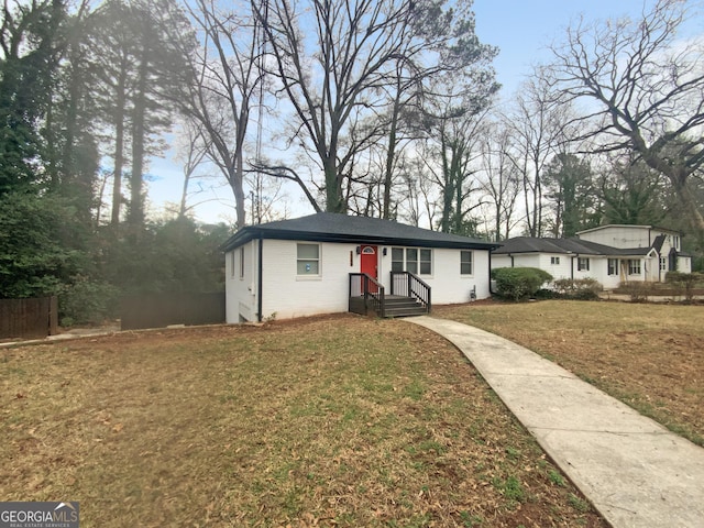 view of front of house with brick siding, fence, and a front yard