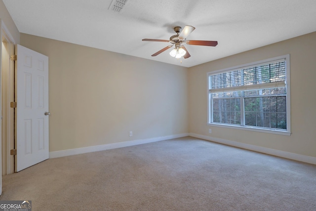 empty room with visible vents, baseboards, light colored carpet, and a ceiling fan