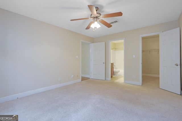 unfurnished bedroom with visible vents, a walk in closet, baseboards, light carpet, and a closet