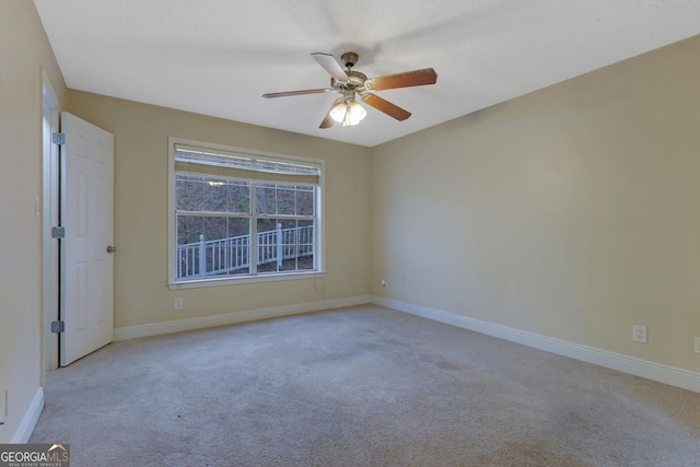 carpeted spare room with a ceiling fan and baseboards