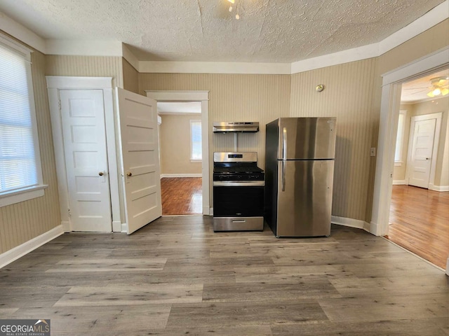 kitchen featuring a textured ceiling, stainless steel appliances, wood finished floors, and under cabinet range hood