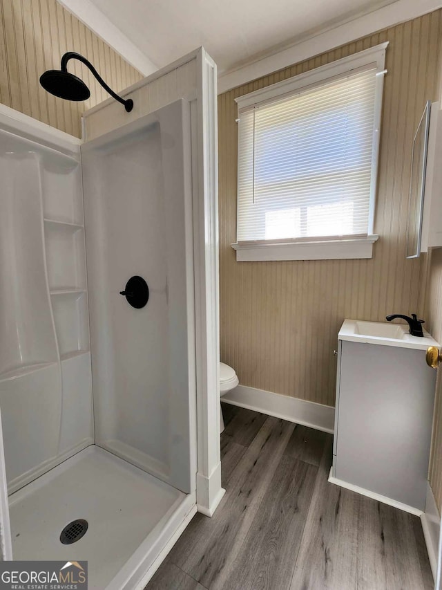 bathroom featuring toilet, wood finished floors, vanity, baseboards, and a shower stall