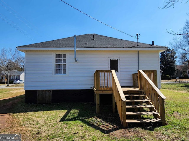 back of house featuring a shingled roof, a lawn, a wooden deck, and stairs