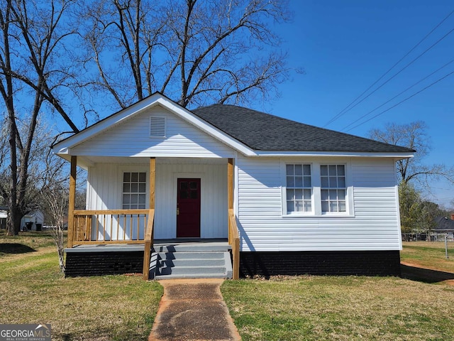 view of front of home with a shingled roof, covered porch, and a front lawn