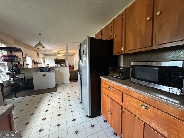 5546 Wellborn Creek Dr, Lithonia, GA 30058 - kitchen featuring stainless steel appliances, brown cabinets, a ceiling fan, light flooring, and dark countertops
