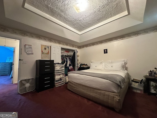 5546 Wellborn Creek Dr, Lithonia, GA 30058 - bedroom featuring a raised ceiling, dark colored carpet, a textured ceiling, and a closet